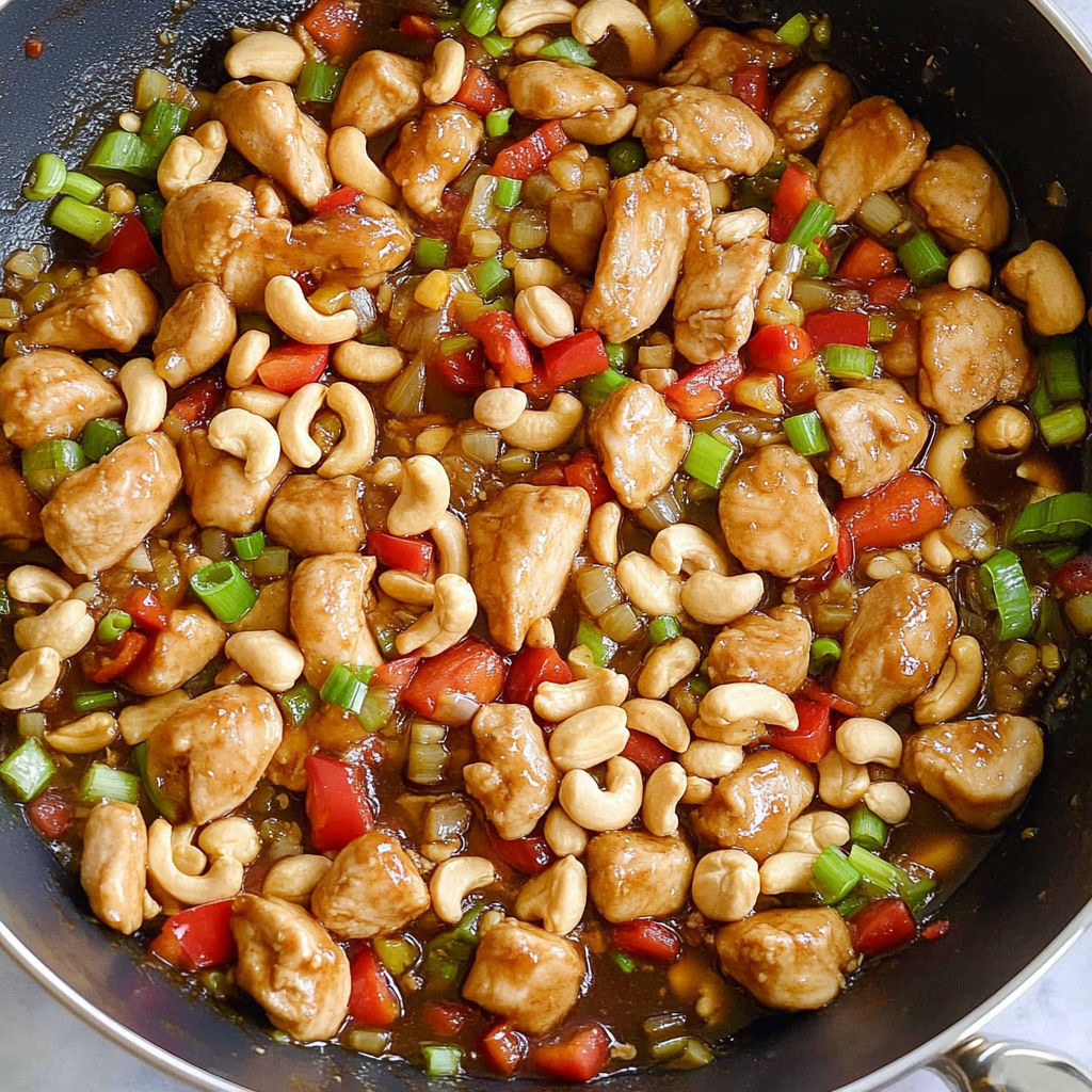 A pan of stir fry with chicken, peppers, and nuts.