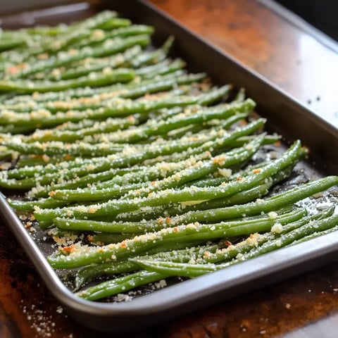 A tray of roasted green beans covered with melted parmesan cheese.