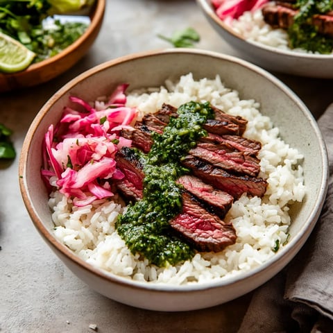 A loaded bowl with seared steak slices, rice, and green chimichurri drizzle.