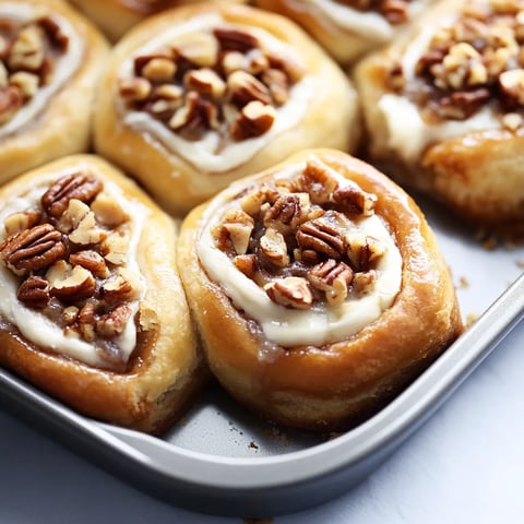 A pan of fluffy pastries loaded with pecans and cream.