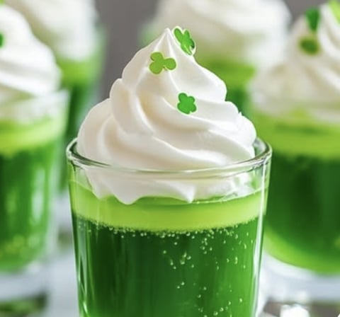 A green drink topped with cream and a leafy garnish.