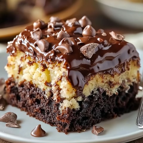 A slice of German Chocolate Poke Cake with chocolate drizzle and chocolate chips on top.
